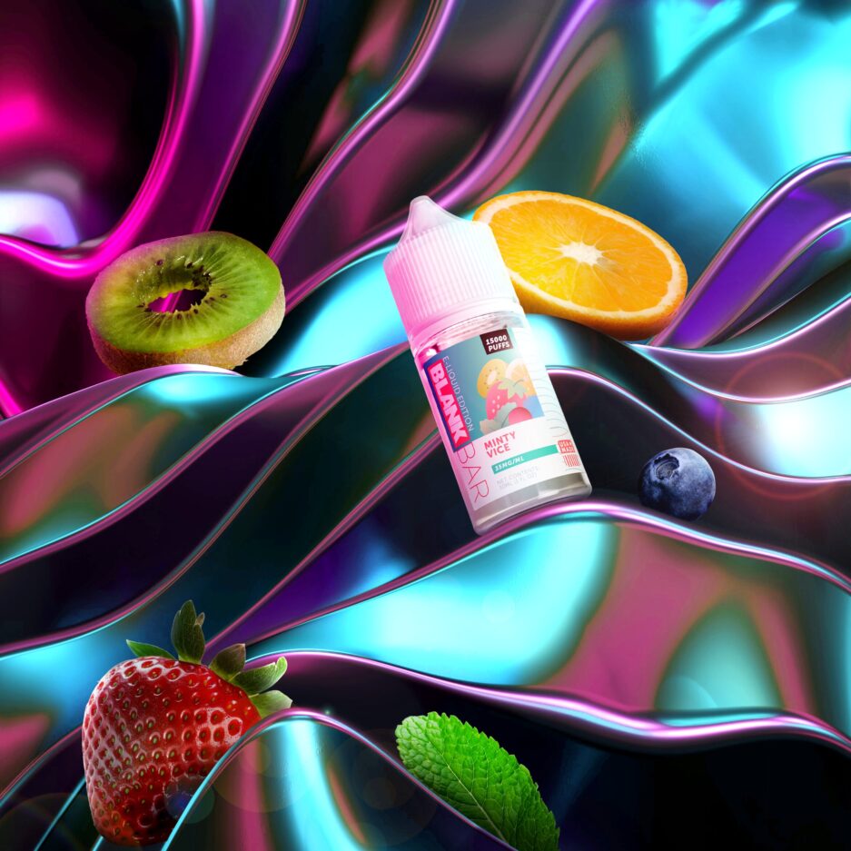 Minty Vice sits angled on an abstract wavy metallic object covering the area, with an orange, kiwi, strawberry, blueberry, and mint leaf exemplifying the ingredients of the product spread out around the image.