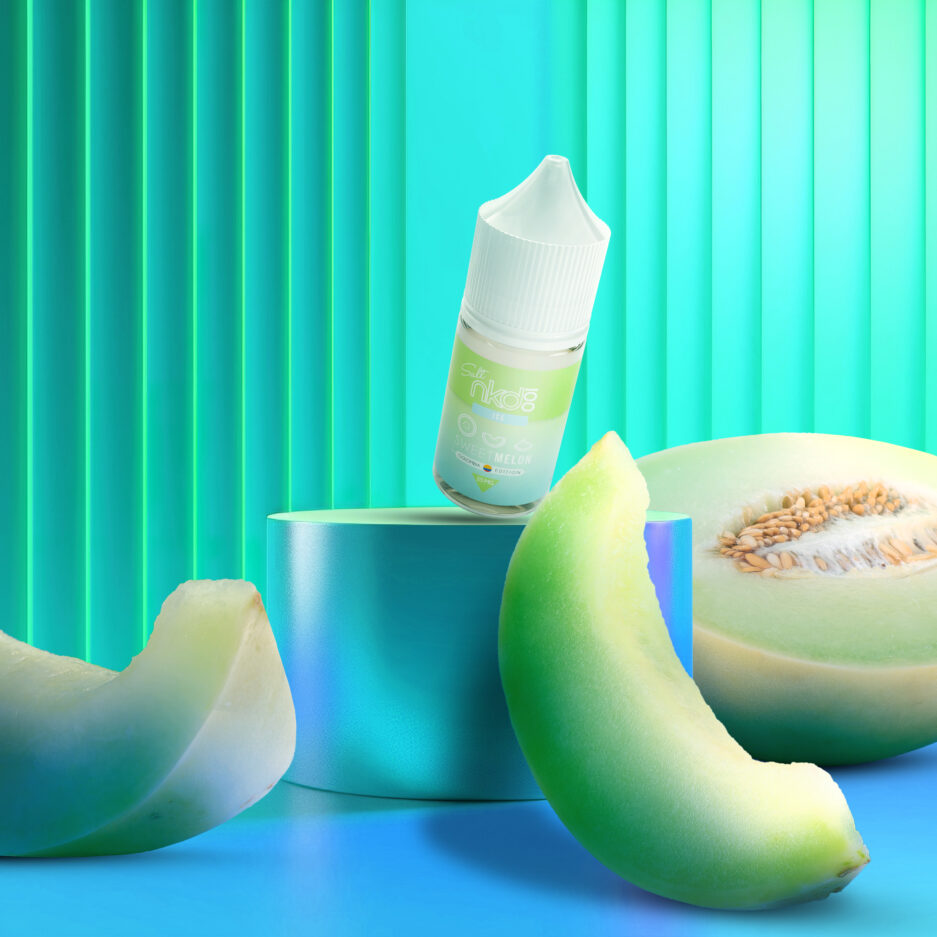 Sweet Melon is angled on a platform with 3 pieces of melon on the ground pointing towards the bottle in a room with neon green and blue color tones.