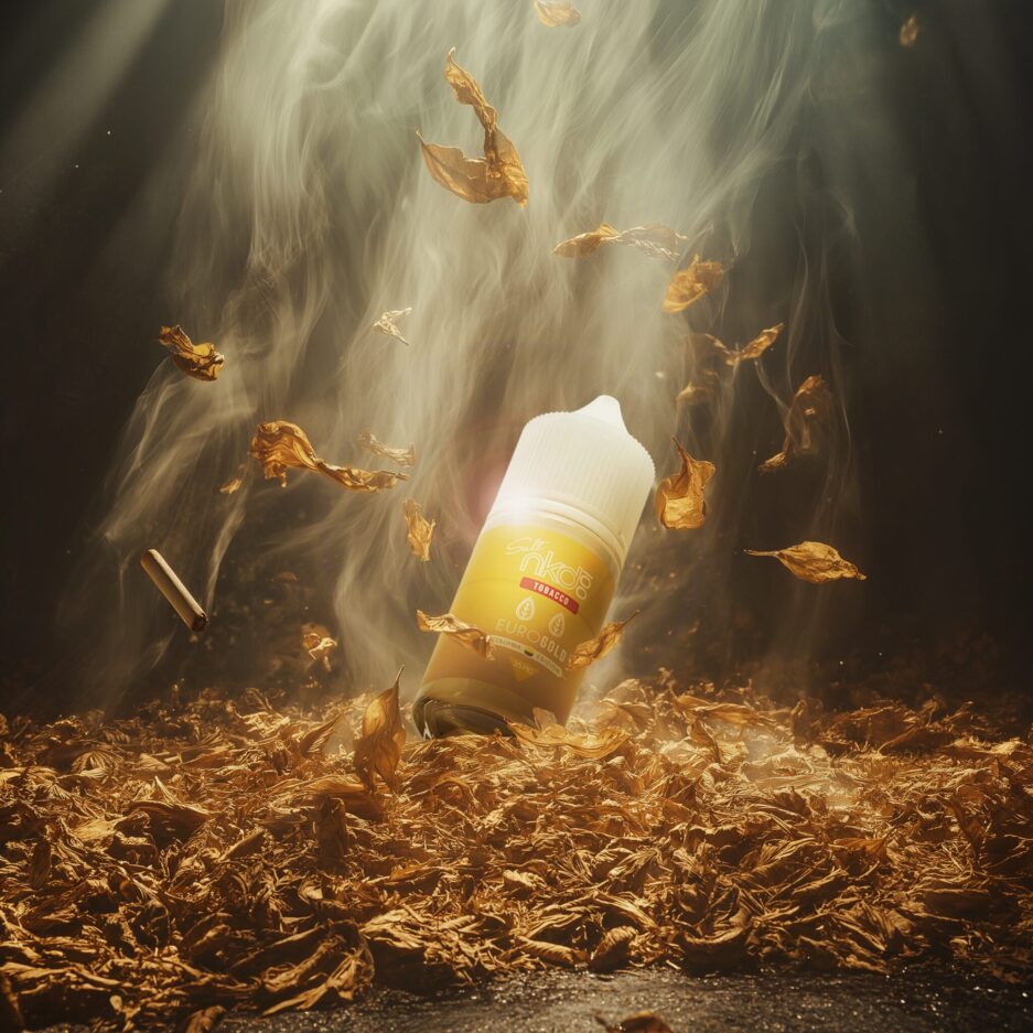 A product set with dramatic lighting, one large light from above illuminating the center of the image. Gold tobacco leafs piled onto the floor with more leafs falling from above. Naked 100 Colombia's Euro Gold sits on top of the pile, Smoke is dissipating throughout the image.